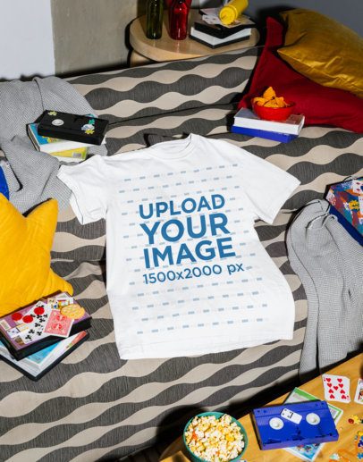 Comfort Colors Mockup of a T-Shirt Lying on a Couch With VHS and Junk Food