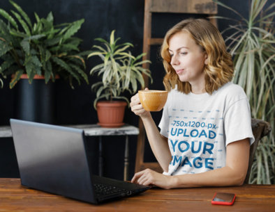 Unisex T-Shirt Mockup Featuring a Woman Working on Her Computer