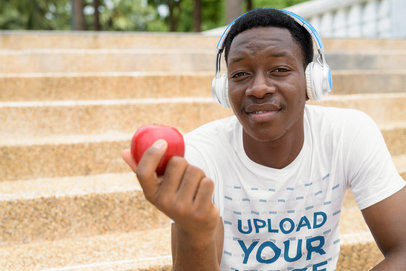 T-Shirt Mockup of a Man Eating an Apple While Listening to Music
