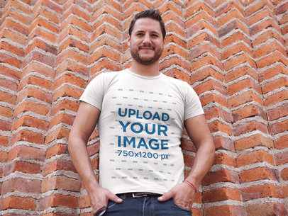 Mockup of a White Guy Wearing a Tshirt While Against a Bricks Wall