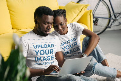 T-Shirt Mockup Featuring a Couple at Home Using a Laptop