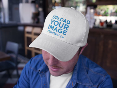 Closeup Mockup Featuring a Dad Hat Being Worn by a Guy at the Bar