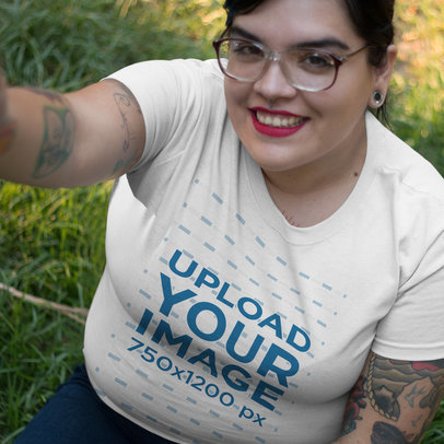 Selfie of a Young Girl Wearing a Plus Size Tshirt Mockup Sitting on the Grass a16009