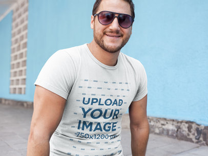 Smiling Middle Aged Man Wearing a T-Shirt Template While Against a Light Blue Wall