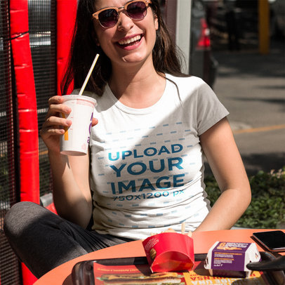 Smiling Customer Drinking a Small Soda While Wearing a Tshirt Mockup Outdoors