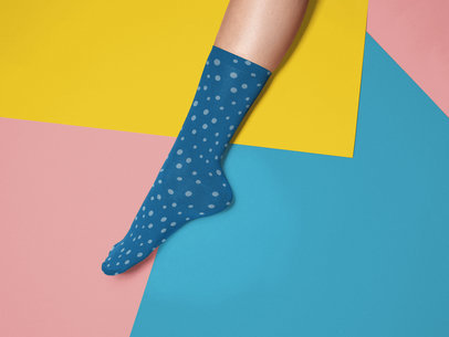Mockup of an Extended Leg Wearing a Sock While Against a Tricolor Surface a15597
