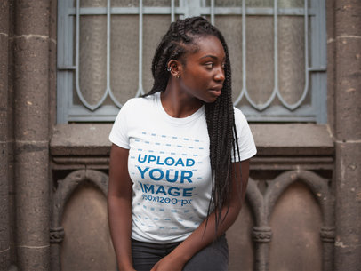 Mockup of a Woman with Locks Looking Away While Wearing a Tee Against a Cathedral Window