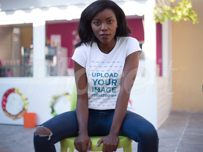 T-shirt Mockup Featuring a Young Woman Wearing a Round Neck Tee While Sitting Down Outdoors 