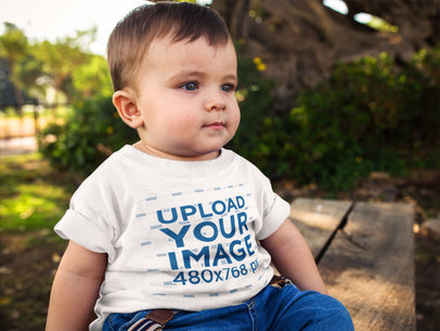Little Baby Boy Wearing a Round Neck Tee Mockup While Sitting Down Outdoors