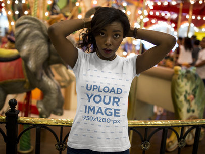 Woman Wearing a T-shirt Mockup While Standing Against a Carousel 