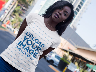 Angled Mockup of a T-Shirt Being Worn by a Woman While at the City