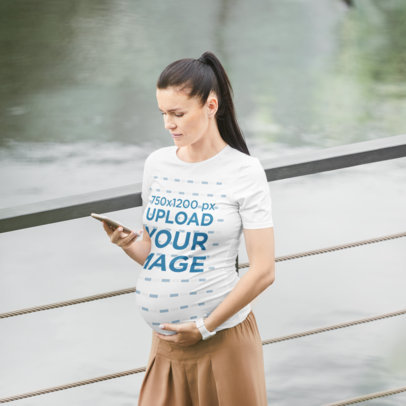 T-Shirt Mockup of a Pregnant Woman Walking While Using Her Smartphone