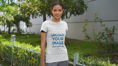 Basic T-Shirt Video of a Happy Young Woman Posing by a Small Garden 3381v