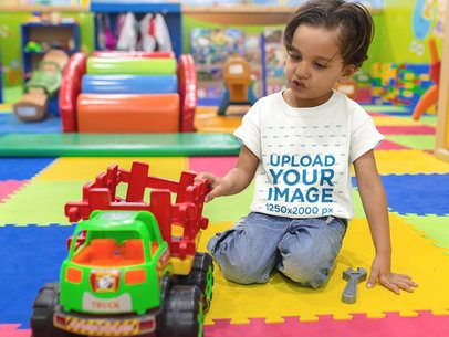 Mockup of a Kid Playing with a Truck While Wearing a T-Shirt Mockup at the Playground