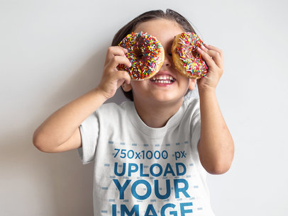 Boy Playing with Donuts While Wearing a T-Shirt Mockup Against a White Wall