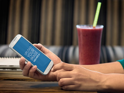 Mockup of a  White Samsung Galaxy 4 On a Woman's Hands in Restaurant
