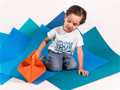 Small Boy Playing with an Orange Paper Boat While Wearing a T-Shirt Mockup