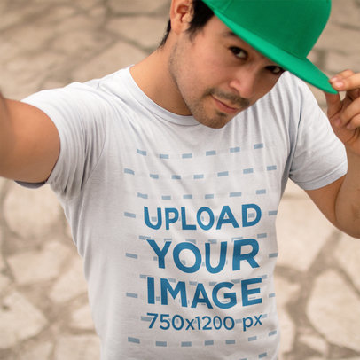 Young Man Wearing a Round Neck Tee Mockup and a Hat While Taking a Selfie