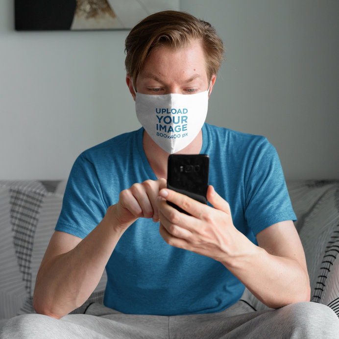 Face Mask Mockup of a Man on His Couch Checking His Phone