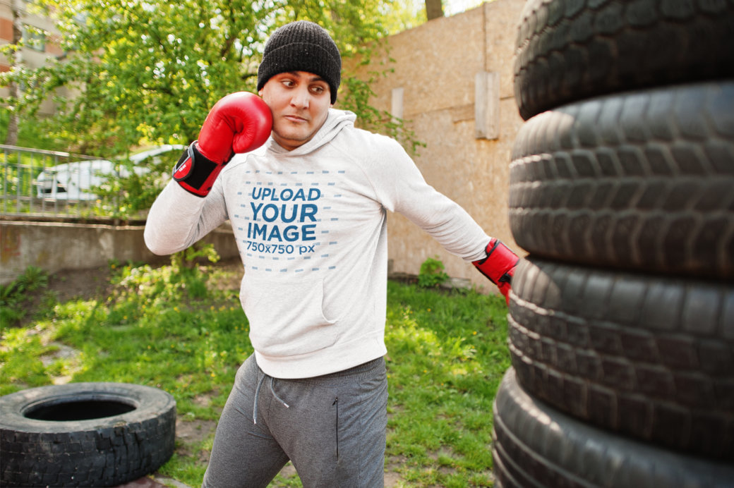 Heathered Hoodie Mockup of a Man Boxing a Pile of Tires