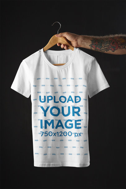 Mockup of a Tattooed Man Holding a T-Shirt on a Hanger