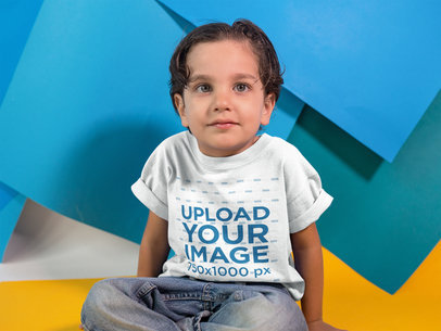 Little White Kid Wearing a Round Neck Tee While Sitting in a Studio