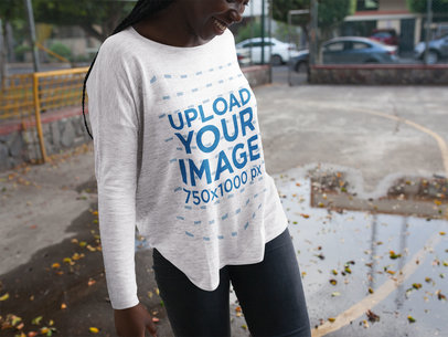 Smiling Woman Wearing a Bella Flowie Long Sleeve Baggy Tee Mockup while at a Park