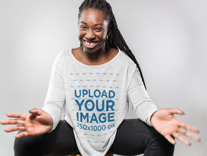 Smiling Woman Wearing a Long Sleeve Heather Off Shoulder Tshirt Mockup Sitting Down Against a White Background a16196
