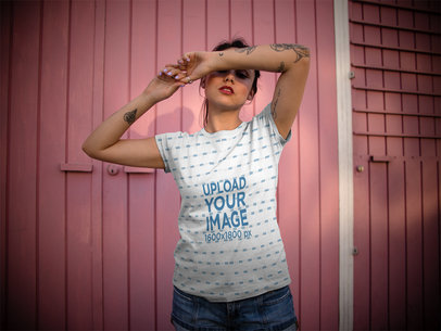 Woman Wearing a Sublimated Tee Mockup While Against a Small Pink Cabin