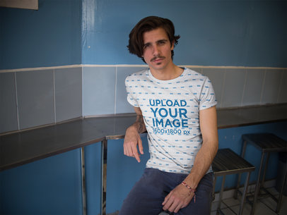 Hipster Dude Wearing a Sublimated Tee Mockup While Waiting for his Food Against a Blue Wall