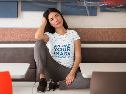 Pretty Woman Sitting Down in a Restaurant While Wearing a Sublimated Tee Mockup