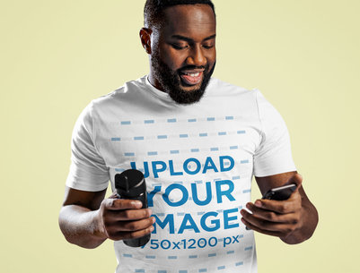 T-Shirt Mockup of a Bearded Man Checking His Phone in a Studio