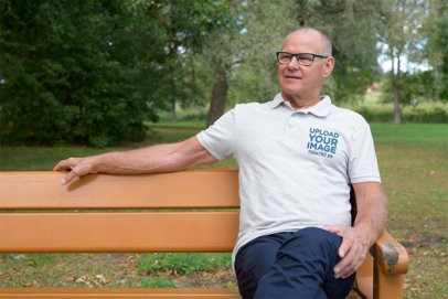 Polo Shirt Mockup of a Senior Man Sitting on a Bench at a Park 44876-r-el2