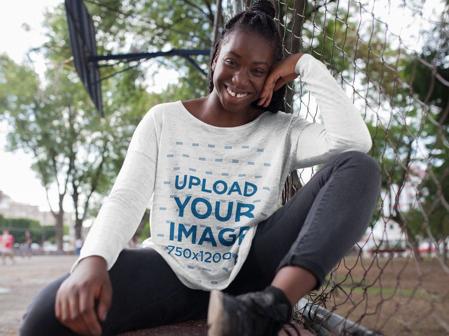 Young Happy Woman with Locs Wearing a Bella Flowie Long Sleeve Loose Tee Mockup While Crouching Outdoors