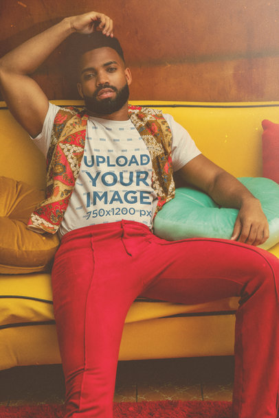 T-Shirt Mockup Featuring a Man with a 70's Outfit Sitting on a Couch