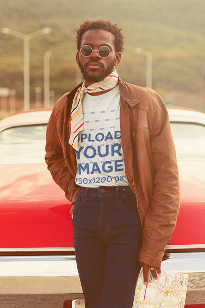 Retro T-Shirt Mockup Featuring a Man Holding a Map and Posing By a Car 