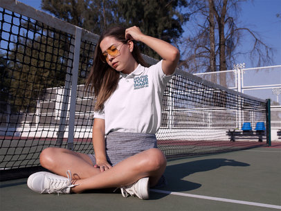 Mockup of a Young Woman Sitting Down in a Tennis Court While Wearing a Polo Shirt