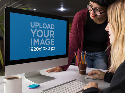 Mockup of a Pair of Women Using an iMac While at the Office