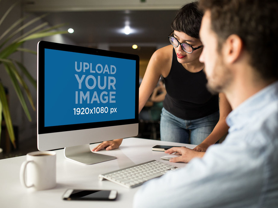 Woman Showing Something in iMac Mockup to Coworker