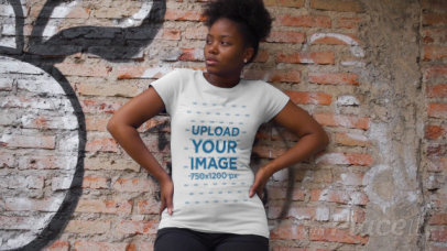T-Shirt Video Featuring a Serious Woman Posing Against a Brick Wall 