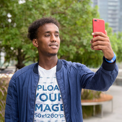 T-Shirt Mockup of a Young Man Taking a Selfie in the City