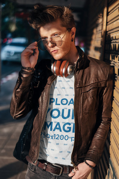 T-Shirt Mockup Featuring a Man With Sunglasses Leaning on a Wall