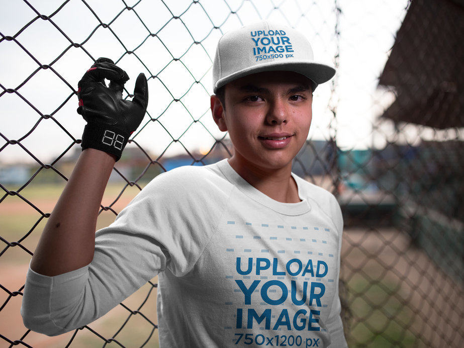 Smiling Teenager Wearing a Baseball Hat Mockup and a Raglan T-Shirt While in the Field