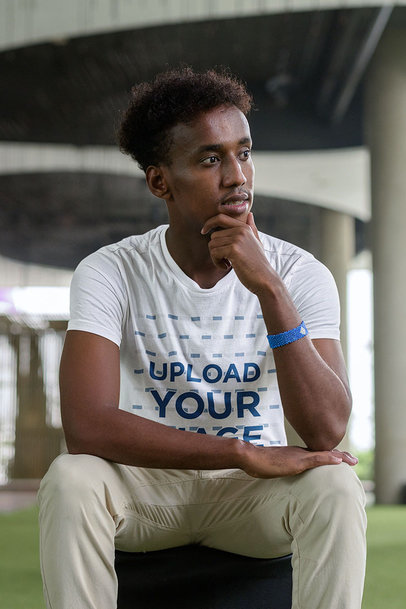 T-Shirt Mockup of a Young Man Sitting at a Terrace