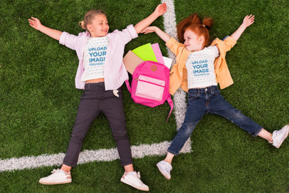 Siblings Day-Themed T-Shirt Mockup Featuring Two Sisters Lying on a Field 