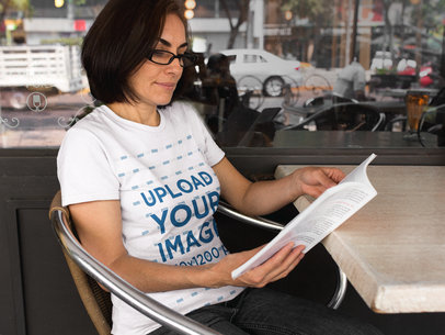 Middle Aged Woman Reading Magazine While Wearing a T-Shirt at a Cafe a15879