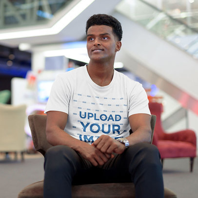T-Shirt Mockup Featuring a Man Sitting on a Brown Couch