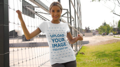T-Shirt Video Featuring a Smiling Woman Posing by a Fence
