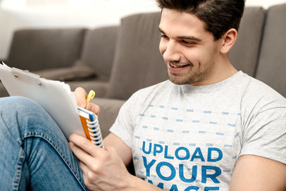 T-Shirt Mockup of a Smiling Man Writing Down Some Notes