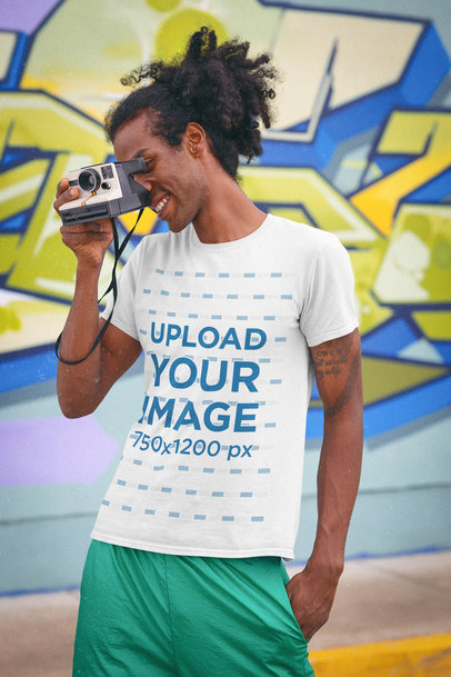 T-Shirt Mockup of a Man Taking a Picture With a Retro Camera